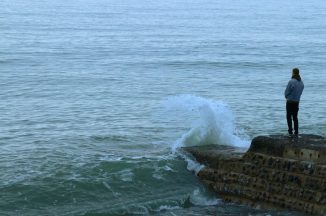 Man grieving looking out onto ocean